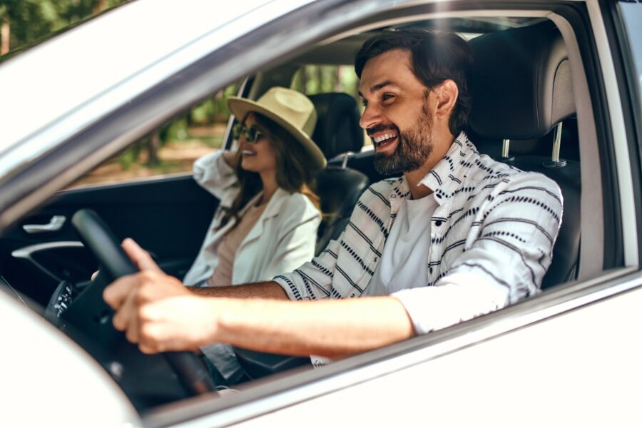 Um casal dentro de um carro branco, viajando