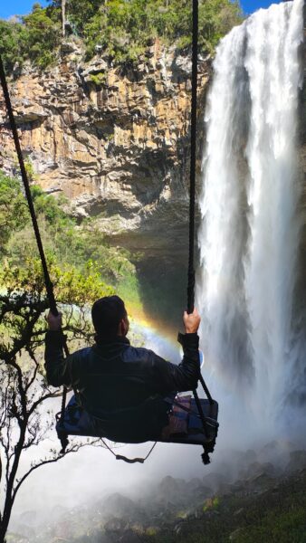 Homem no balanço em frente a Cascata do Caracol, em Canela - RS